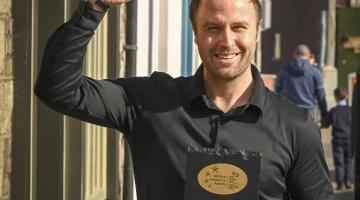 Man holding award with arm raised